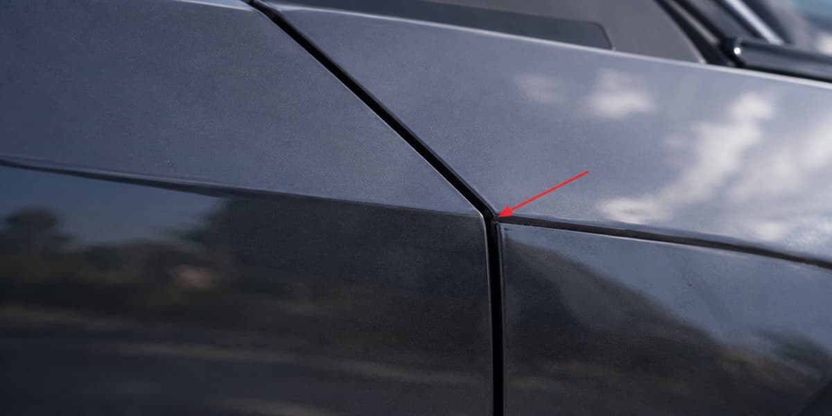 Uneven door panel gap on a Tesla, marked with a red arrow